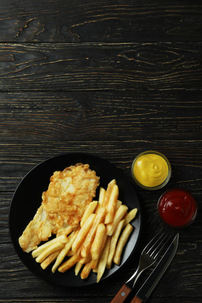 istock Plate with tasty fried fish and chips on wooden background 1310058527