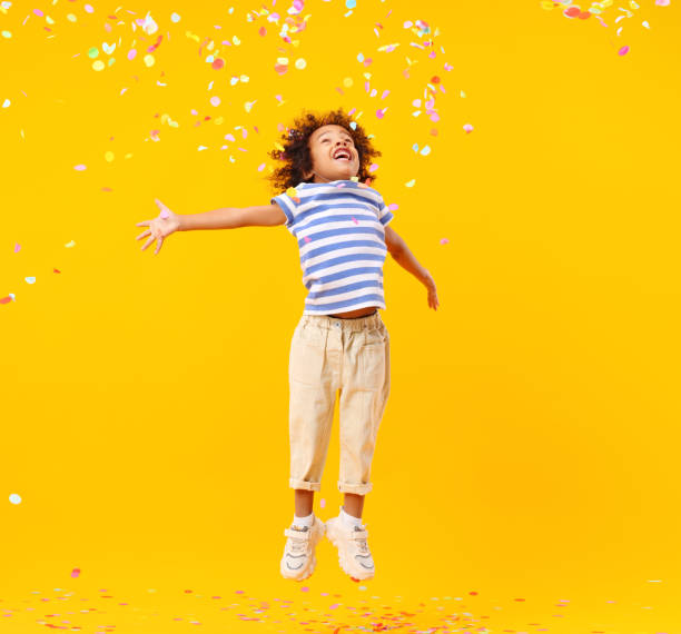 istock Excited African American kid jumping and catching confetti in studio 1310059211