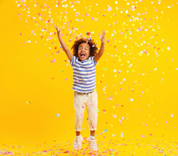 istock Excited African American kid jumping and catching confetti in studio 1310059308