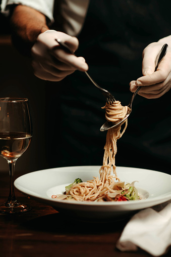 Close-up of a chef's hand winding pasta on a fork