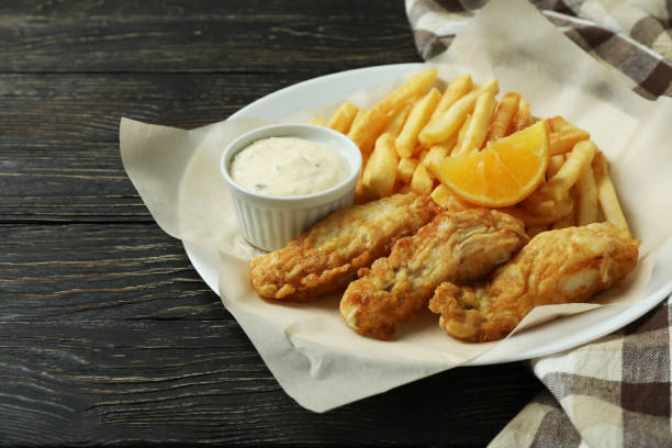 istock Plate with fried fish and chips on wooden background with kitchen towel 1310060830