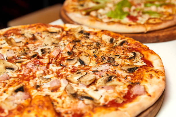 istock Fresh pizza with bacon, mushrooms and cheese on a light background. Close-up, selective focus 1310062058