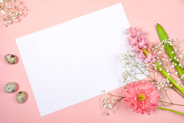istock Easter festive greeting card with white sheet with copy space for text, quail eggs and spring flowers on pastel pink. 1310062299