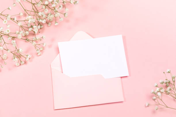 Pastel pink festive layout with envelope, empty sheet, white gypsophila flowers. Copy space for text. Mock up.
