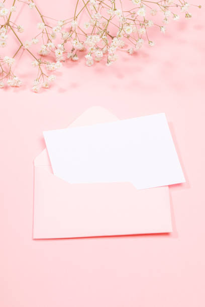istock Pastel pink festive greeting card with empty white sheet in envelope and white gypsophila flowers. Copy space for text. 1310062309