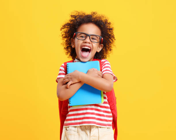 istock Cheerful little ethnic schoolchild with backpack and textbooks in yellow studio 1310063200