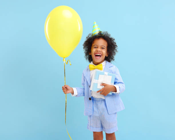 entzückende ethnische kind mit geburtstagsgeschenk und ballon in den händen - 16611 stock-fotos und bilder