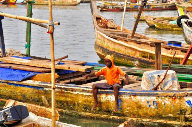 chłopiec siedzi na tradycyjnej afrykańskiej łodzi rybackiej - rowboat fishing africa fishing industry zdjęcia i obrazy z banku zdjęć