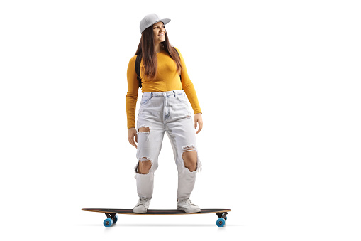 Full length shot of a skater girl riding a longboard isolated on white background
