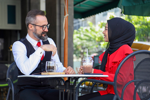 Arabic businessman has meeting and discussing with Muslim lady at the halal coffee shop for Muslim culture concept