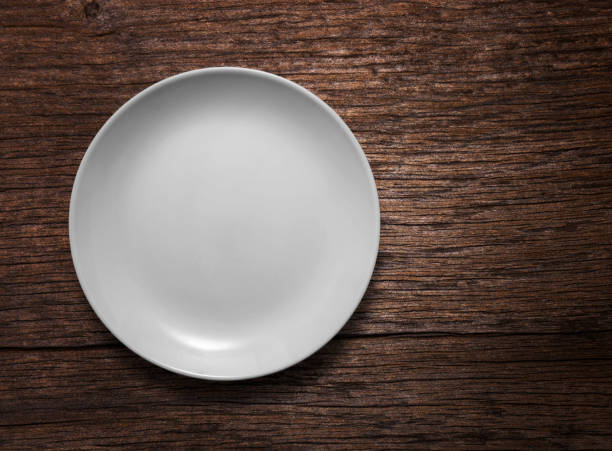 istock Blank white ceramic round dish on wooden desk background 1310066252