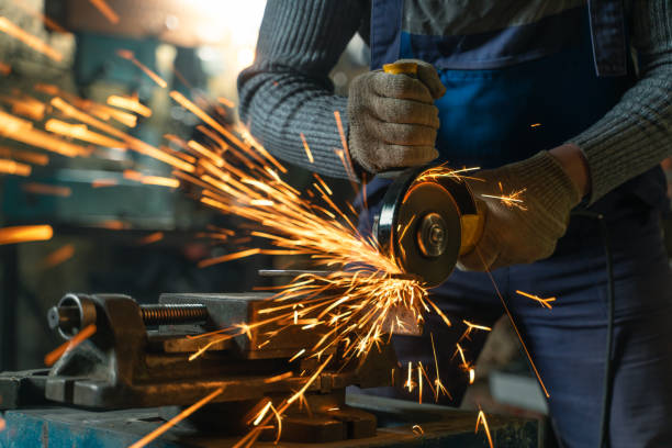 istock Locksmith in special clothes and goggles works in production. Metal processing with angle grinder. Sparks in metalworking 1310066258