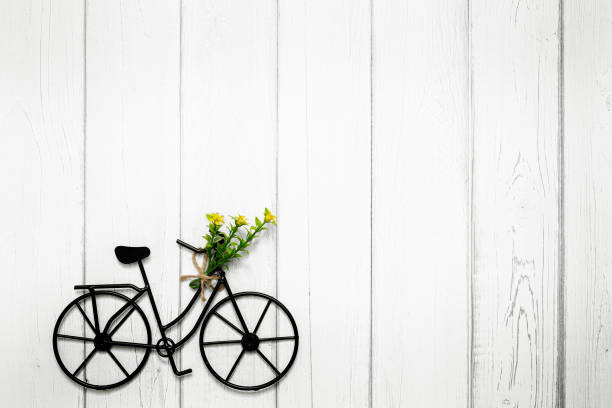 Small wire bicycle with flowers on wooden background