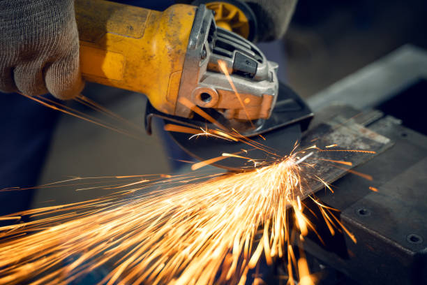 istock Locksmith in special clothes and goggles works in production. Metal processing with angle grinder. Sparks in metalworking 1310066521
