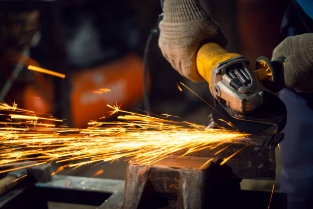 istock Locksmith in special clothes and goggles works in production. Metal processing with angle grinder. Sparks in metalworking 1310066604