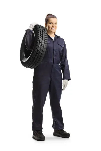 Full length portrait of a female mechanic worker carrying a tire isolated on white background