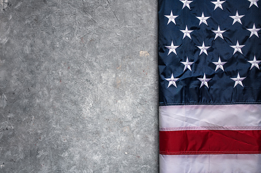 Flag of USA on light grey concrete background.
Empty space provided for text placement for US celebrations such as: Memorial Day, Independence Day, etc.