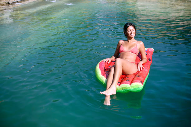 Pregnant woman swims in a baseen on her back