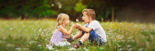 Photo of happy children play outdoor with the dandelions