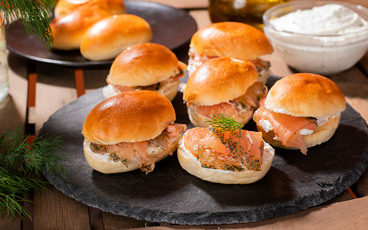 Marinated salmon in buns with cheese and dill on the table ready to eat
