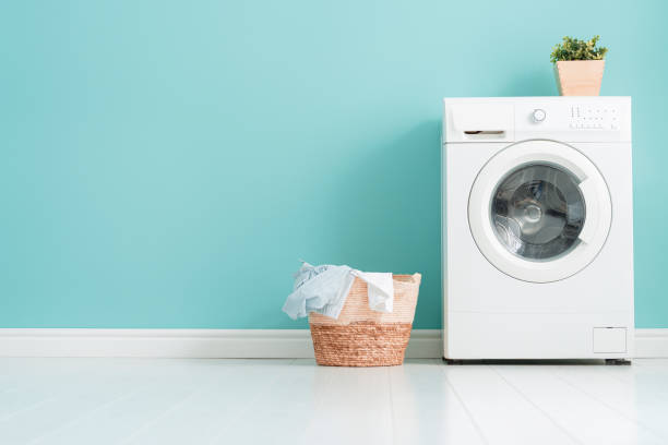 laundry room with a washing machine Interior of laundry room with a washing machine on bright teal wall background. washing machine stock pictures, royalty-free photos & images