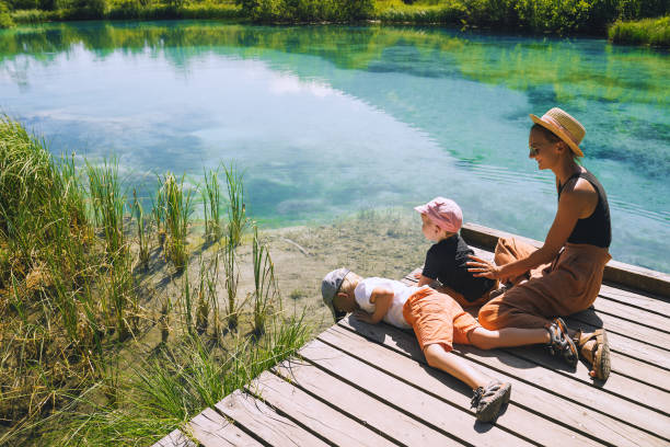 familia de turistas en la naturaleza. joven con niños pequeños en puente de madera de fondo natural verde. madre e hijo juntos. viaje de aventura eslovenia, europa. - baby mother summer park fotografías e imágenes de stock