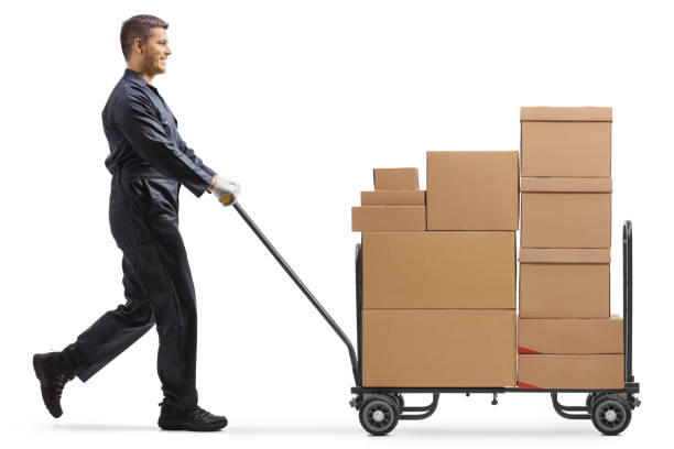 istock Male worker in a uniform pushing a hand truck loaded with boxes 1310077292