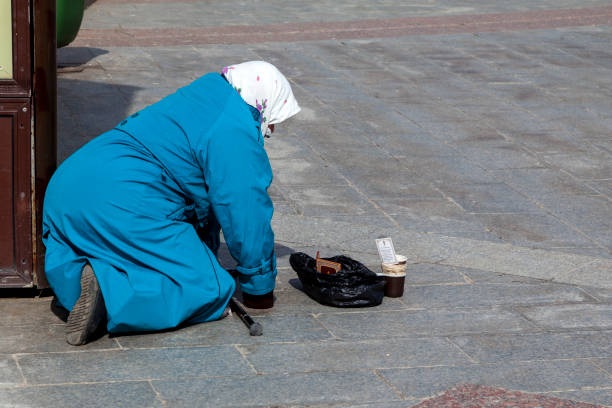 Elderly poor Gypsy woman begs for alms on a European road