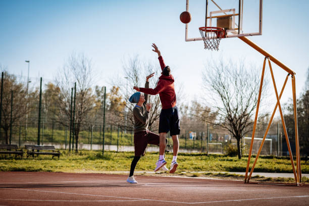 istock Man and woman playing basketball outdoors, man doing a slam dunk 1310079617