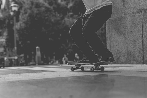 Black and white photo of man`s legs on skateboard