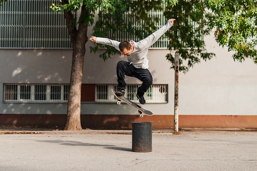 Male skateboarder jumping over the bucket