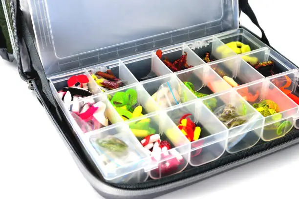 Photo of A box with a variety of silicone baits lies in a fishing bag, white background close-up