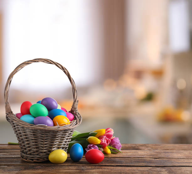 istock Colorful Easter eggs in wicker basket and tulips on wooden table indoors, space for text 1310088714