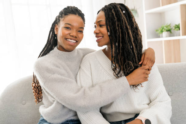 istock Mother and daughter sitting on sofa at home 1310089487