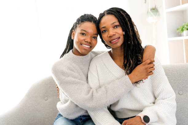 istock Mother and daughter sitting on sofa at home 1310089489