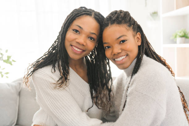 istock Mother and daughter sitting on sofa at home 1310089490