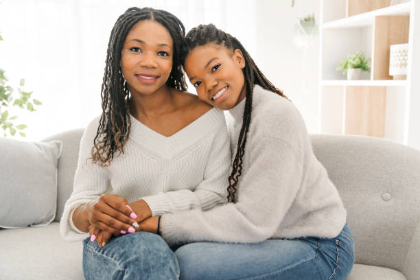 istock Mother and daughter sitting on sofa at home 1310089504