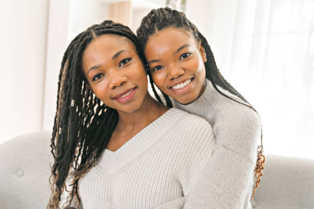 istock Mother and daughter sitting on sofa at home 1310089509