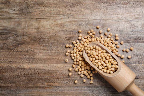 istock Scoop with chickpeas on wooden table, flat lay. space for text 1310089533