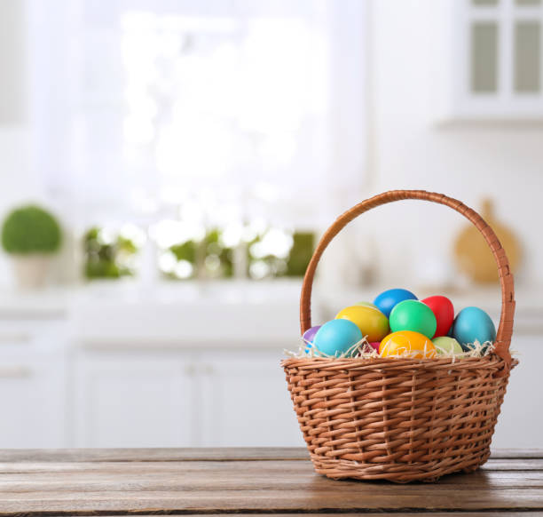 istock Colorful Easter eggs in wicker basket on wooden table indoors, space for text 1310089616