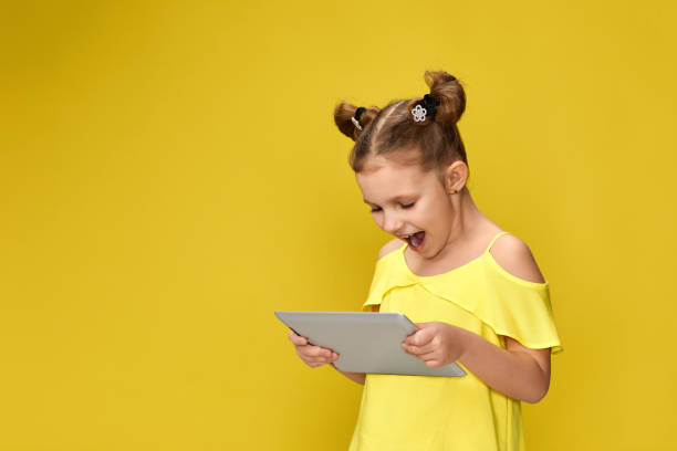 istock child girl in yellow t-shirt using digital tablet 1310090783