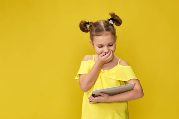 istock child girl in yellow t-shirt using digital tablet 1310090831