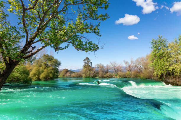 hermoso paisaje natural de la cascada de manavgat en el parque nacional en el soleado día de primavera. color azul único del agua con salpicaduras, side, antalya, turquía - water waterfall sky seascape fotografías e imágenes de stock