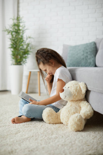istock little child girl with teddy bear using digital tablet. 1310092392