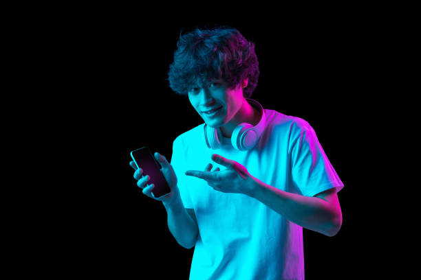 istock Young Caucasian man showing phone screen isolated over dark background in neon 1310094982