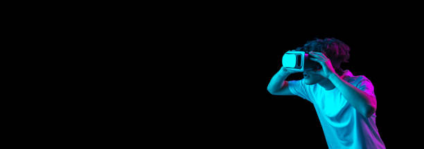 istock Young man using VR headset isolated over dark background in neon light 1310094983