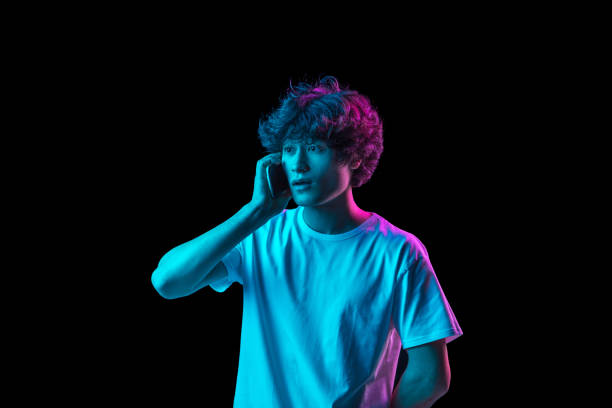 istock Young Caucasian man talking on phone isolated over dark background in neon light 1310095048