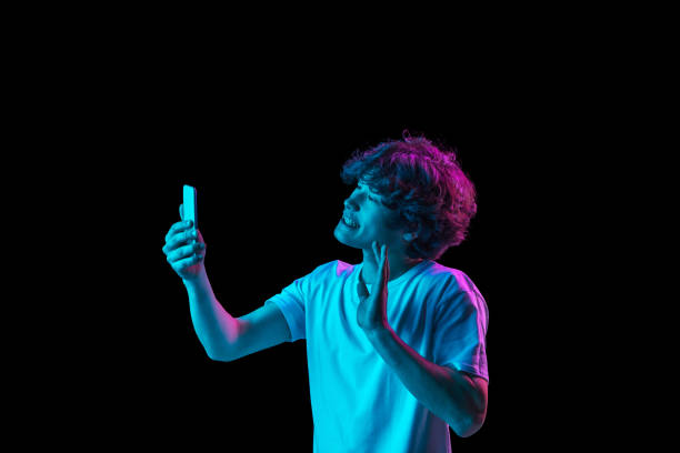 istock Young Caucasian man talking on phone isolated over dark background in neon light 1310095063