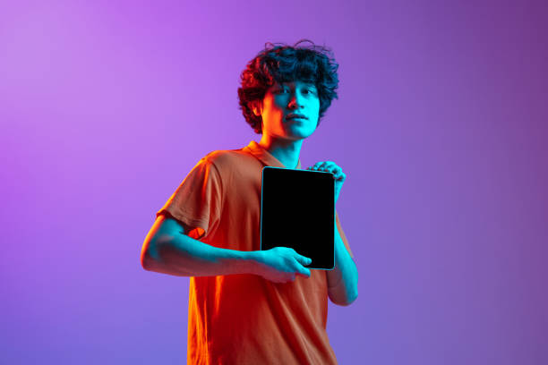 istock Half-length man s portrait with digital tablet on background in neon light 1310095583
