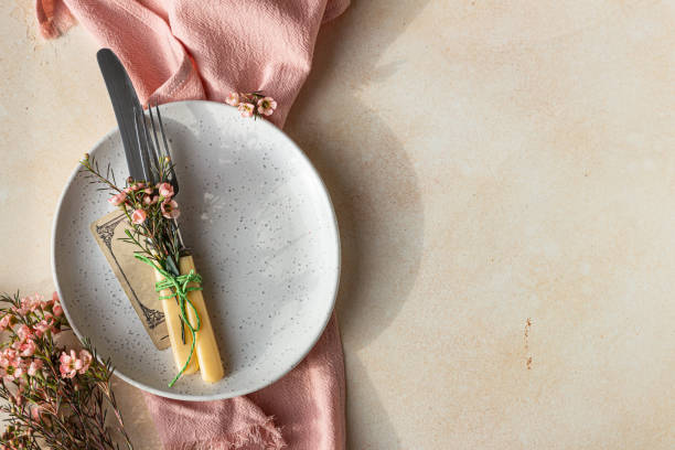 istock Easter table setting background with plate, cutlery set and pink flowers. Empty plate, advertising, menu. Bright sunlight and hard shadows photography trend. 1310095837